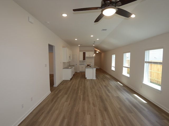 31911 Splendor Dr, Fulshear, TX 77441 - unfurnished living room featuring baseboards, a sink, wood finished floors, vaulted ceiling, and recessed lighting
