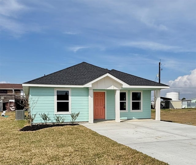 view of front of property featuring a front yard, roof with shingles, and central AC