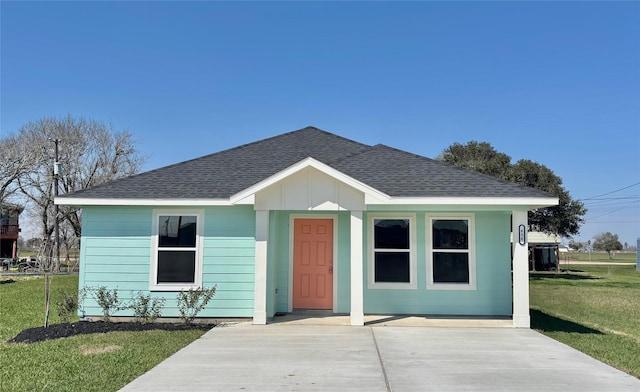 bungalow-style house with board and batten siding, roof with shingles, and a front lawn