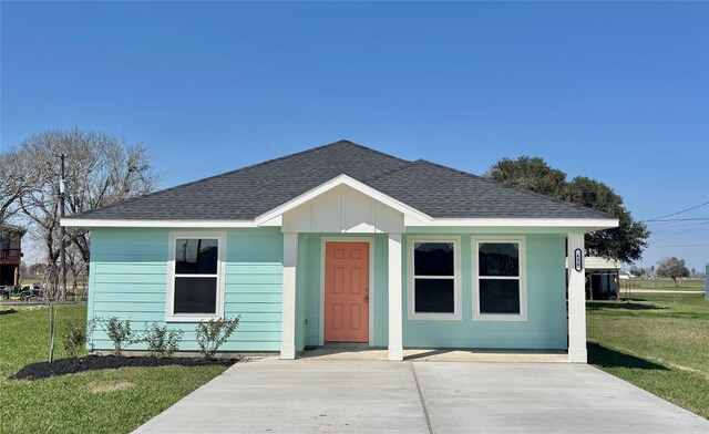 bungalow-style house with board and batten siding, roof with shingles, and a front lawn