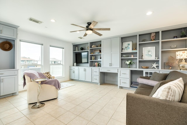 tiled living room featuring ceiling fan and built in desk