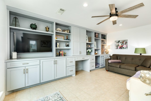 tiled living room featuring ceiling fan and built in desk