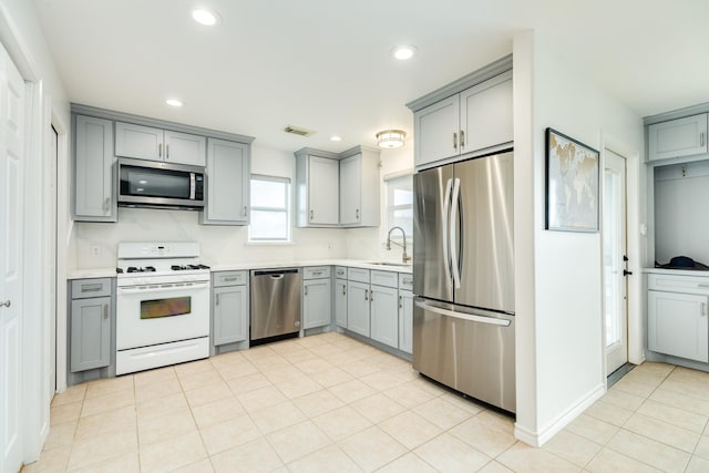 kitchen with stainless steel appliances, gray cabinetry, and sink