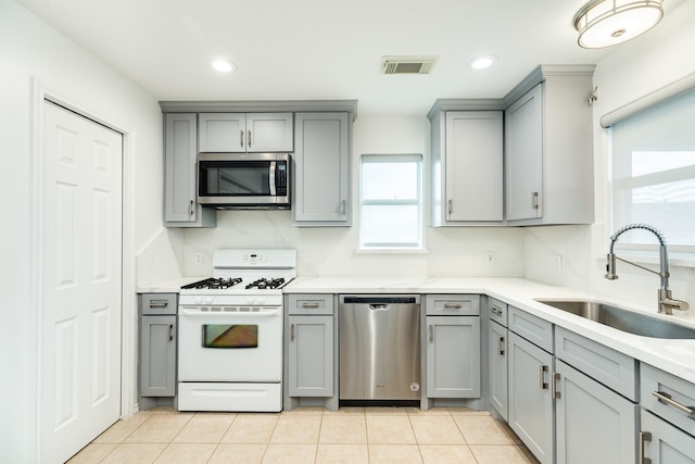 kitchen with sink, appliances with stainless steel finishes, gray cabinetry, and tasteful backsplash