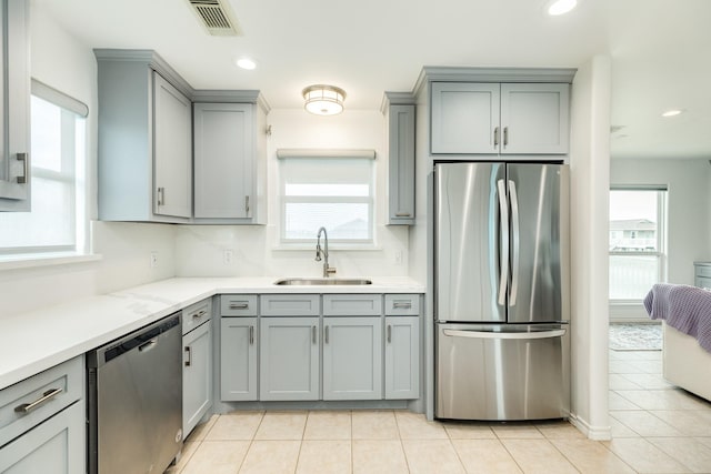 kitchen with light tile patterned flooring, sink, stainless steel appliances, and gray cabinetry