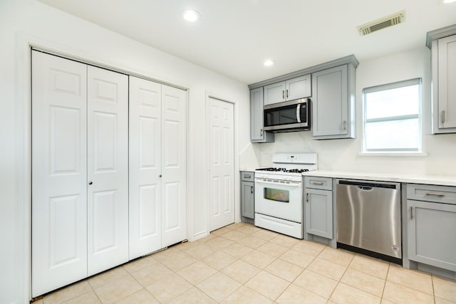 kitchen with appliances with stainless steel finishes, light tile patterned floors, and gray cabinetry