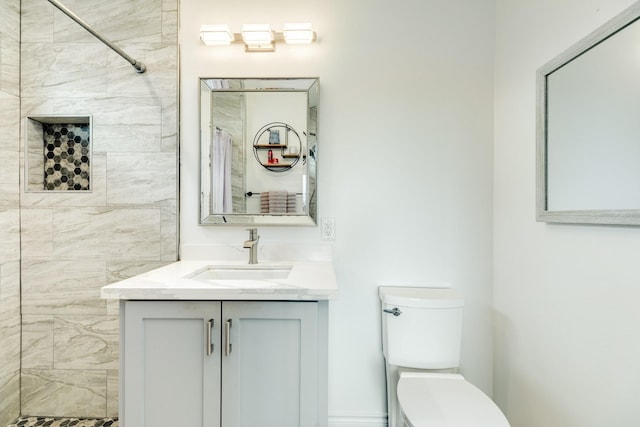 bathroom with vanity, tiled shower, and toilet