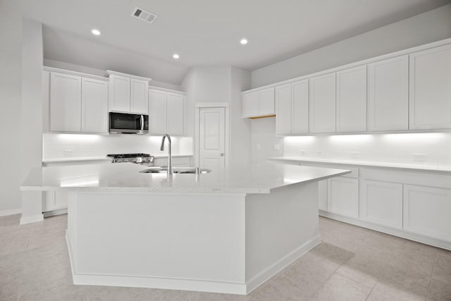 kitchen with a center island with sink, sink, white cabinets, and decorative backsplash