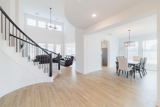 dining space featuring light wood-type flooring, plenty of natural light, and ceiling fan with notable chandelier