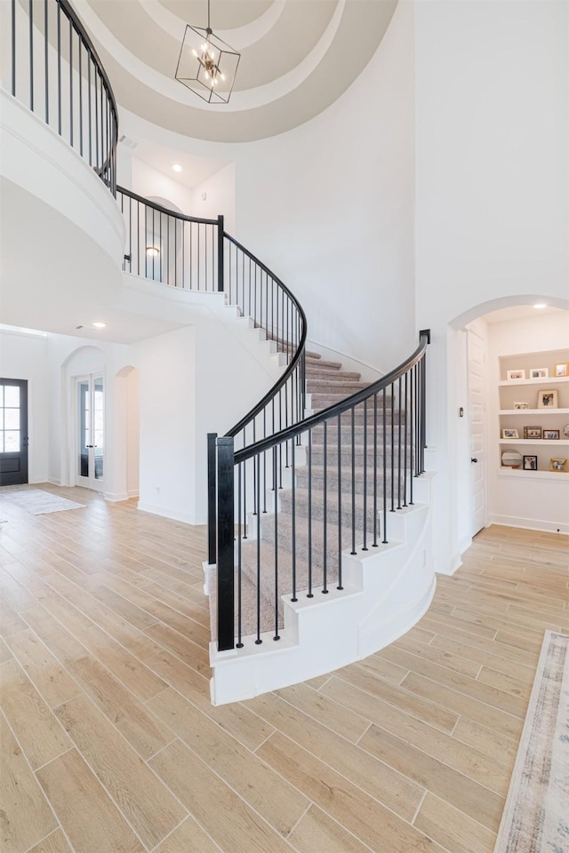 staircase with hardwood / wood-style flooring, a high ceiling, and a notable chandelier