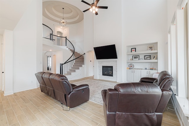 living room with ceiling fan, a high ceiling, and built in features