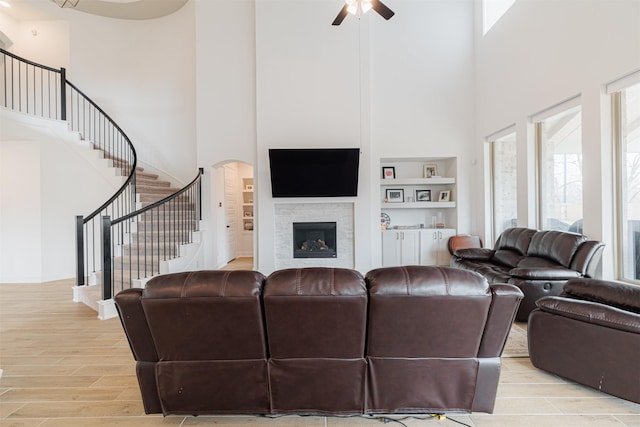 living room featuring ceiling fan, light hardwood / wood-style floors, and a high ceiling