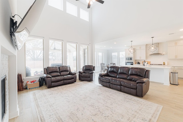 living room with sink, a stone fireplace, plenty of natural light, and light hardwood / wood-style flooring