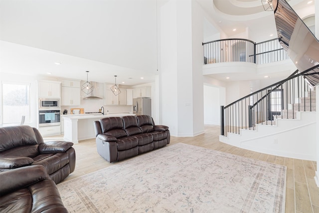 living room featuring a high ceiling, sink, and light hardwood / wood-style flooring