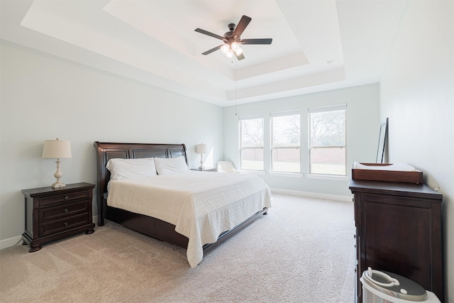 carpeted bedroom with a raised ceiling and ceiling fan