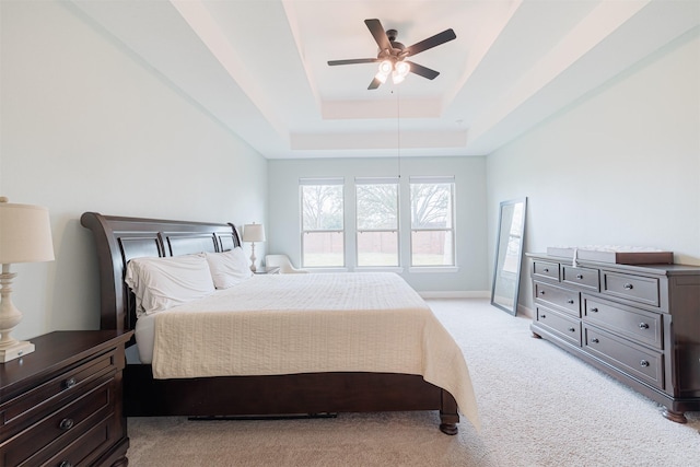 bedroom featuring a tray ceiling, light colored carpet, and ceiling fan