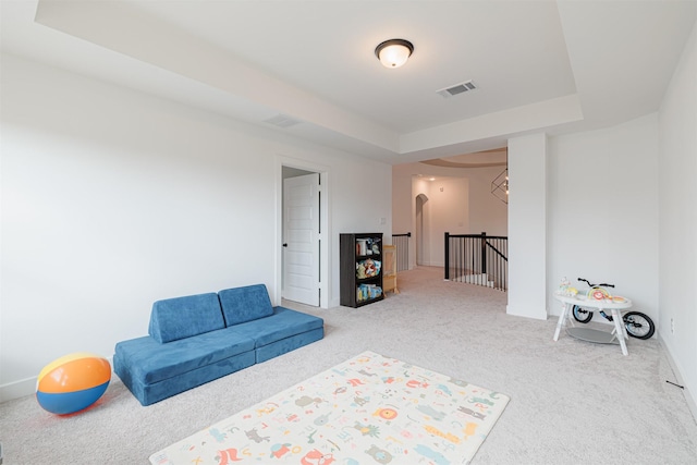 sitting room with a tray ceiling and carpet flooring