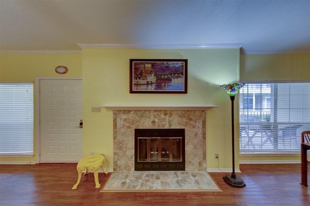 living room featuring wood-type flooring, crown molding, and a fireplace