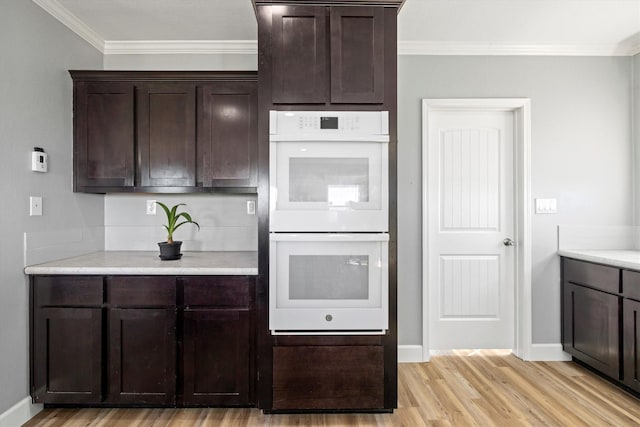 1623 Bay Meadows St, Galveston, TX 77554 - kitchen featuring ornamental molding, light countertops, dark brown cabinets, light wood-style floors, and white double oven
