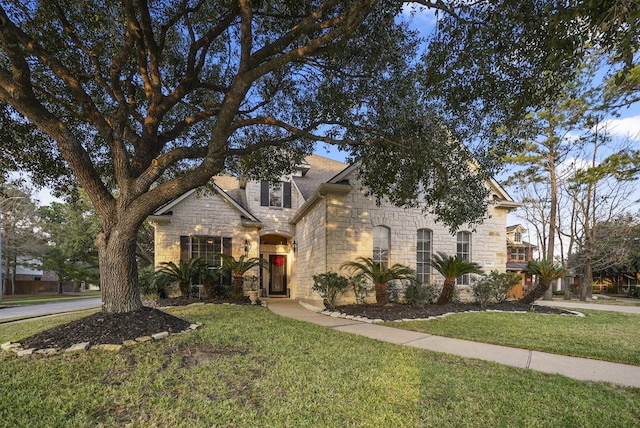 view of front of home featuring stone siding and a front lawn