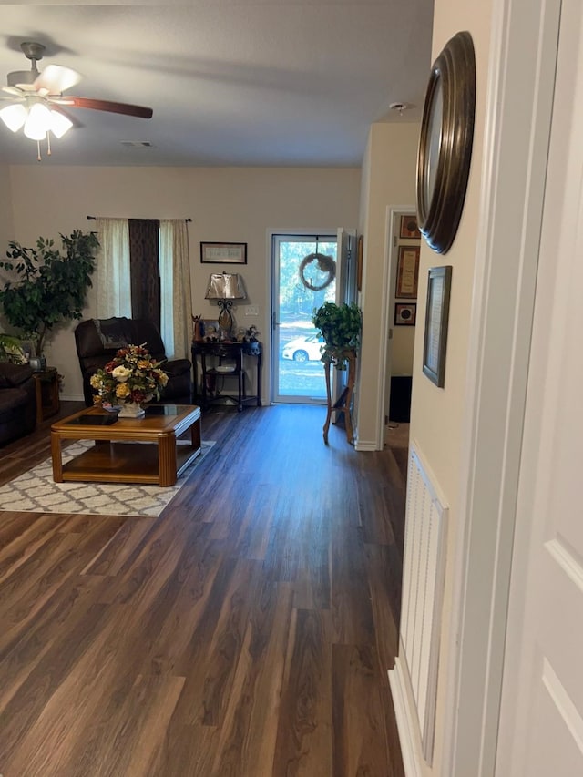 living room featuring dark wood-type flooring and ceiling fan