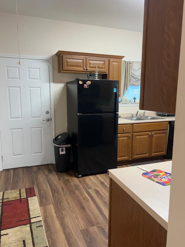 kitchen with sink, dark hardwood / wood-style flooring, and black fridge