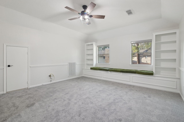 unfurnished room with vaulted ceiling, ceiling fan, built in shelves, and carpet floors