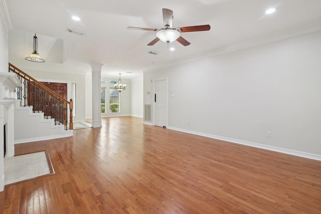 unfurnished living room featuring decorative columns, ornamental molding, light wood-type flooring, and ceiling fan with notable chandelier