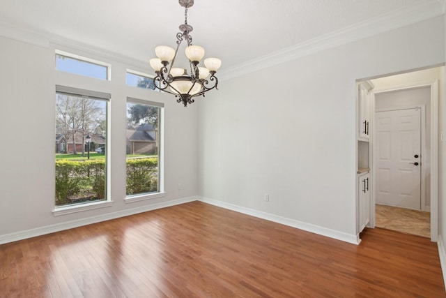 unfurnished dining area featuring crown molding, a chandelier, and wood-type flooring