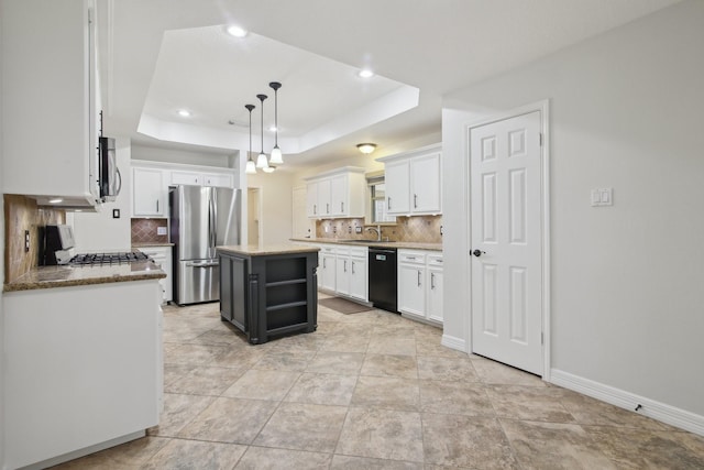 kitchen featuring stainless steel appliances, hanging light fixtures, a kitchen island, a raised ceiling, and white cabinets