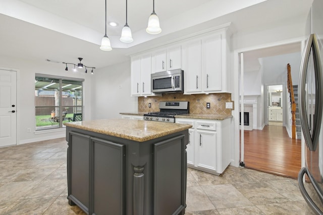 kitchen featuring white cabinets, hanging light fixtures, appliances with stainless steel finishes, and a kitchen island