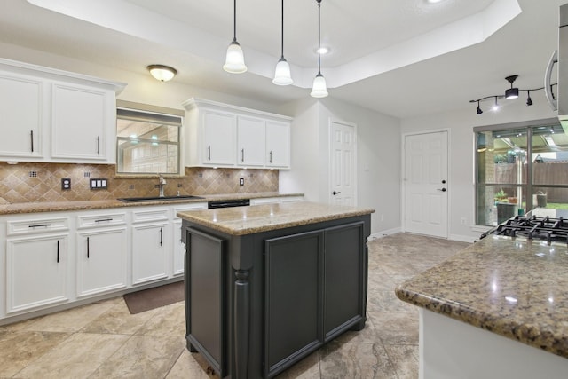 kitchen with sink, white cabinets, a center island, and a tray ceiling