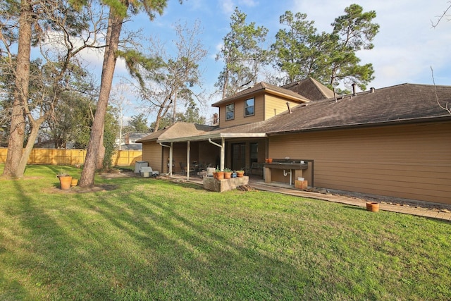 back of property with a yard, a patio, and a hot tub