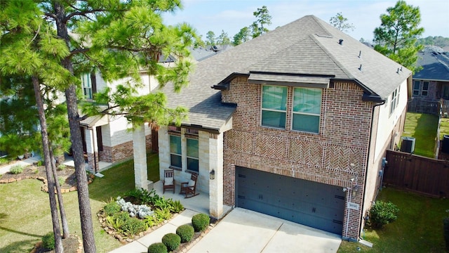 view of front facade featuring brick siding, roof with shingles, concrete driveway, cooling unit, and stone siding