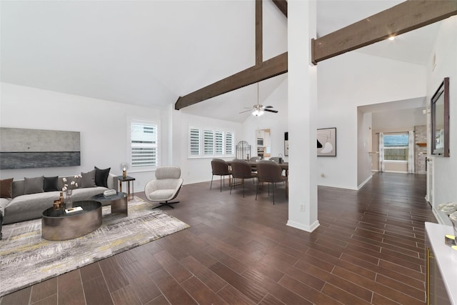 living room with ceiling fan, dark wood-type flooring, beamed ceiling, and a wealth of natural light