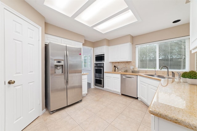 kitchen with white cabinets, stainless steel appliances, tasteful backsplash, and sink