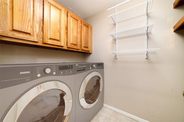 laundry area featuring washing machine and dryer, cabinets, and light tile patterned floors