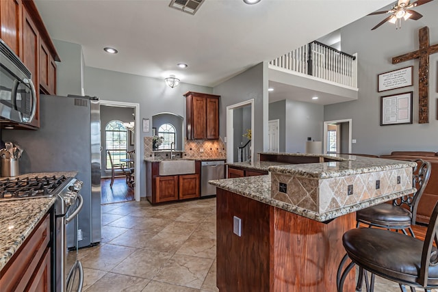 kitchen featuring visible vents, decorative backsplash, appliances with stainless steel finishes, a kitchen bar, and a sink