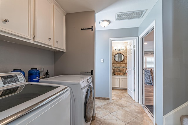 washroom featuring visible vents, cabinet space, washer and clothes dryer, and baseboards