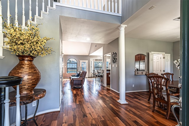 entryway with a high ceiling, hardwood / wood-style flooring, decorative columns, and baseboards