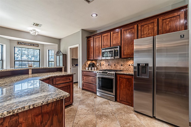 kitchen featuring appliances with stainless steel finishes, stone countertops, visible vents, and tasteful backsplash