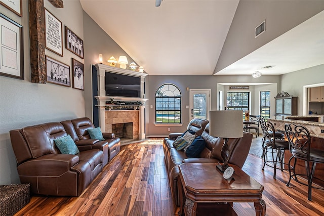 living area featuring visible vents, hardwood / wood-style floors, a tile fireplace, and a wealth of natural light