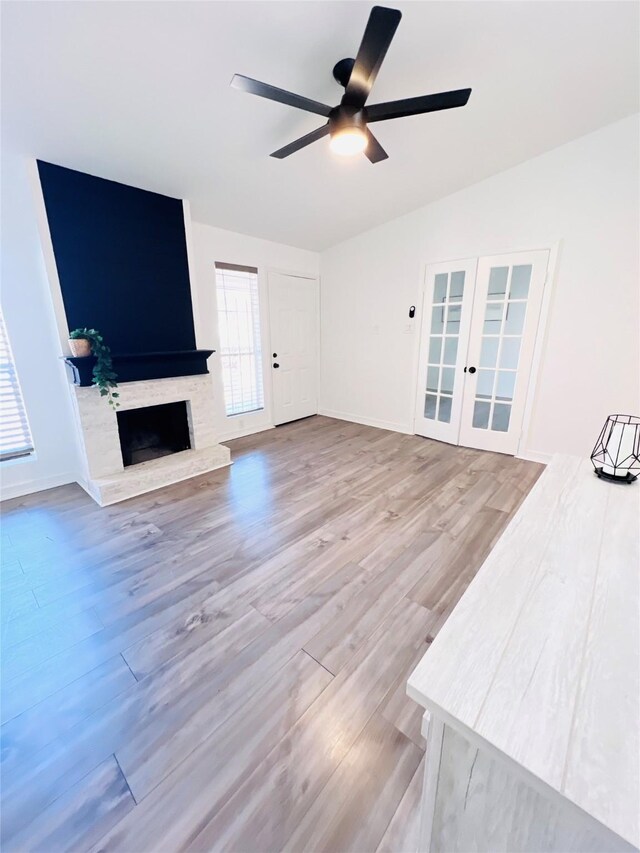 2110 Wilcrest Dr Unit 235, Houston, TX 77042 - unfurnished living room featuring ceiling fan, a fireplace with raised hearth, wood finished floors, french doors, and baseboards