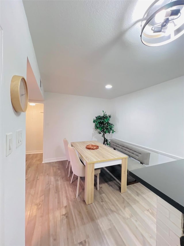 dining room with light wood finished floors, visible vents, baseboards, and a textured ceiling