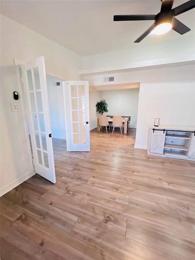 unfurnished room with baseboards, visible vents, ceiling fan, wood finished floors, and french doors