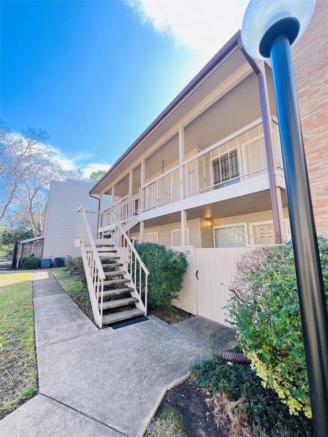 view of building exterior featuring fence and stairway