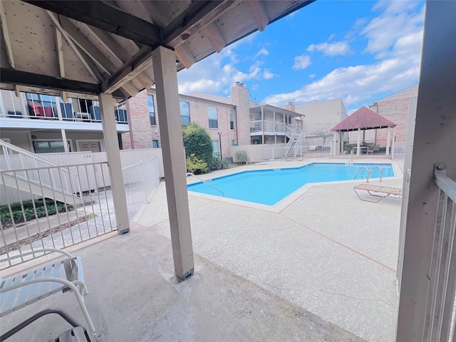 pool with a patio area, fence, and a gazebo