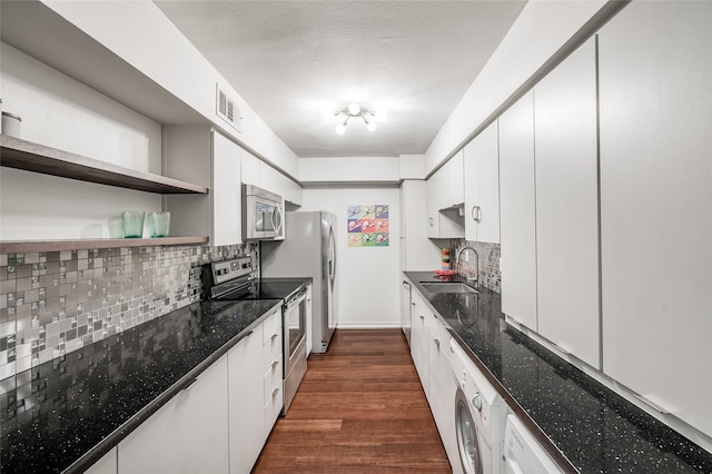 kitchen with appliances with stainless steel finishes, sink, dark wood-type flooring, washer / clothes dryer, and white cabinets