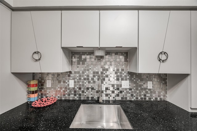 kitchen featuring dark stone countertops, white cabinetry, and sink