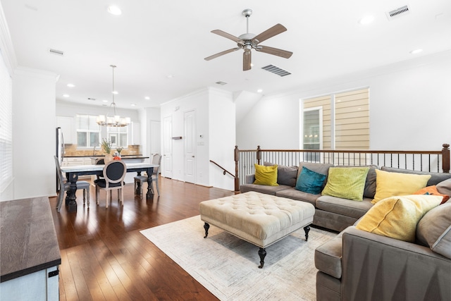 living area with dark wood-style floors, visible vents, and ornamental molding